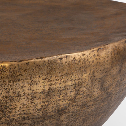 A beautifully hammered aluminum and an antique gold finish coffee table in front of an off-white sofa.