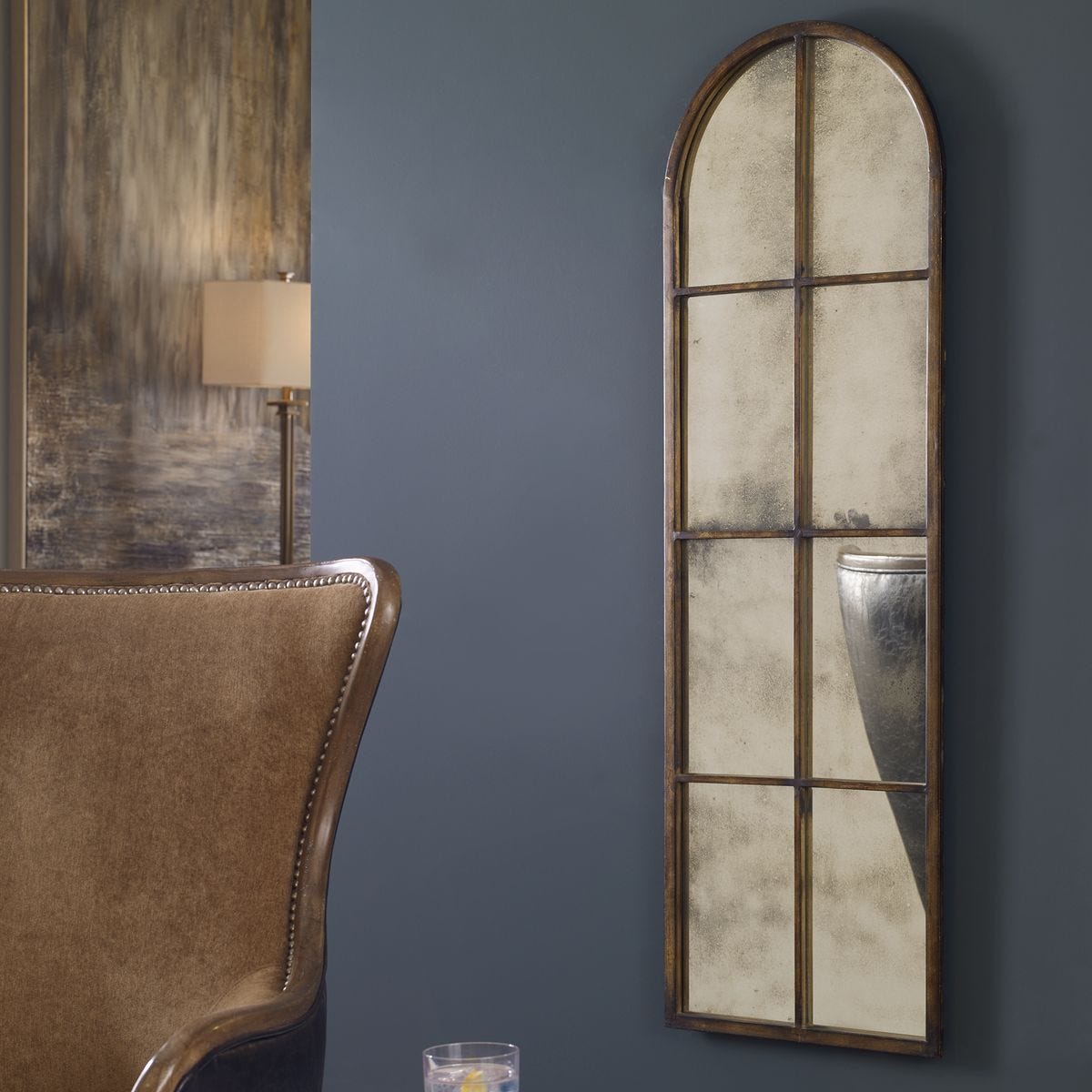 Decorative mirror with grid design on a dark blue wall next to a brown chair.