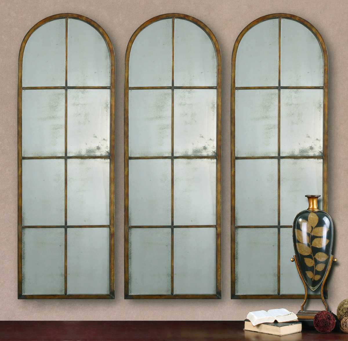 Three arched mirrors with grid designs on a beige wall.