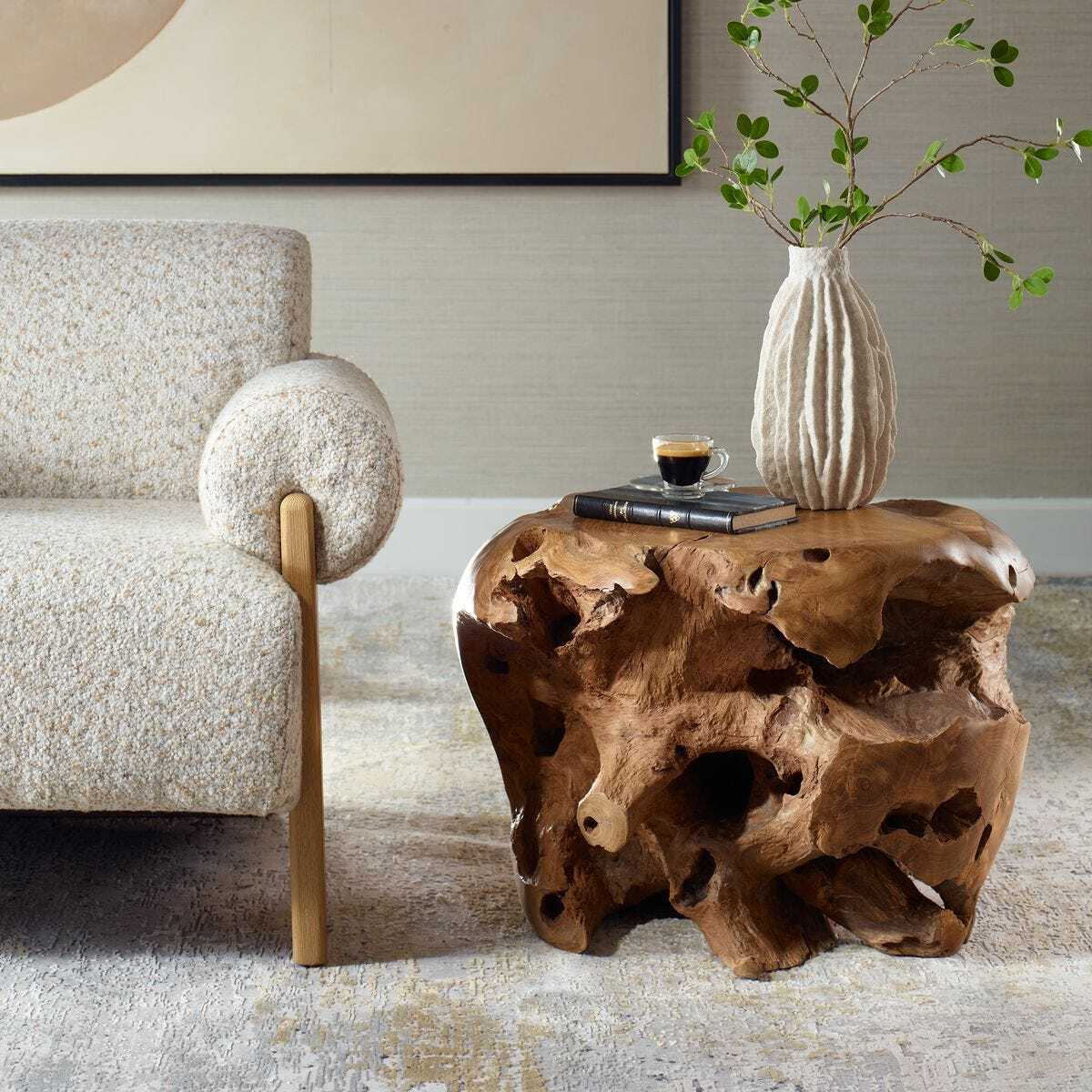 Wooden side table with a textured surface next to a textured armchair in a room.
