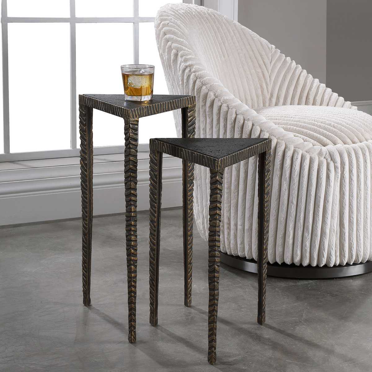 White textured chair with two small black side tables in a room with large windows.