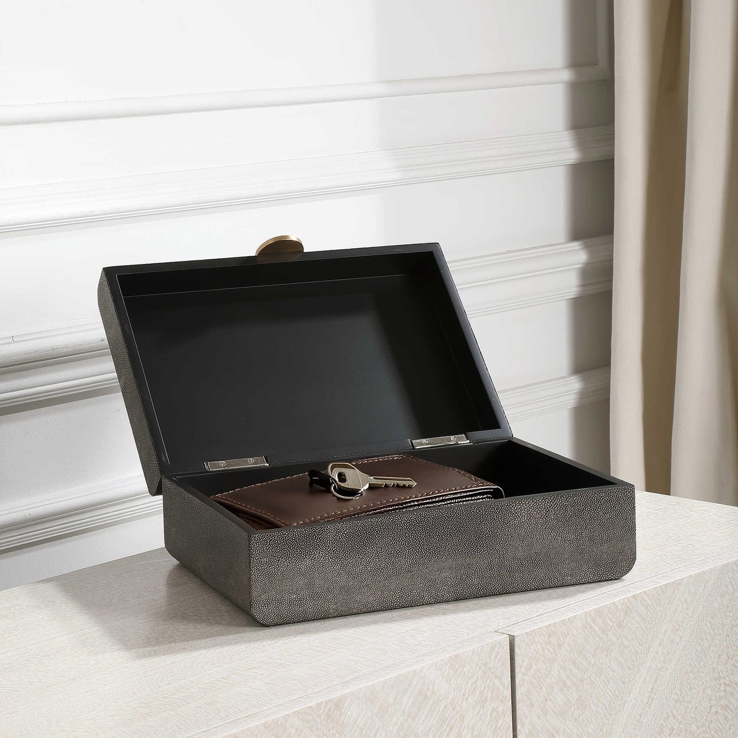 Gray box open on a white console with wallet and keys inside