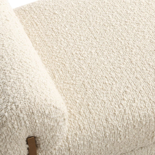 White boucle bench with gold frame and abstract textured piece of art in living room with floor lamp.