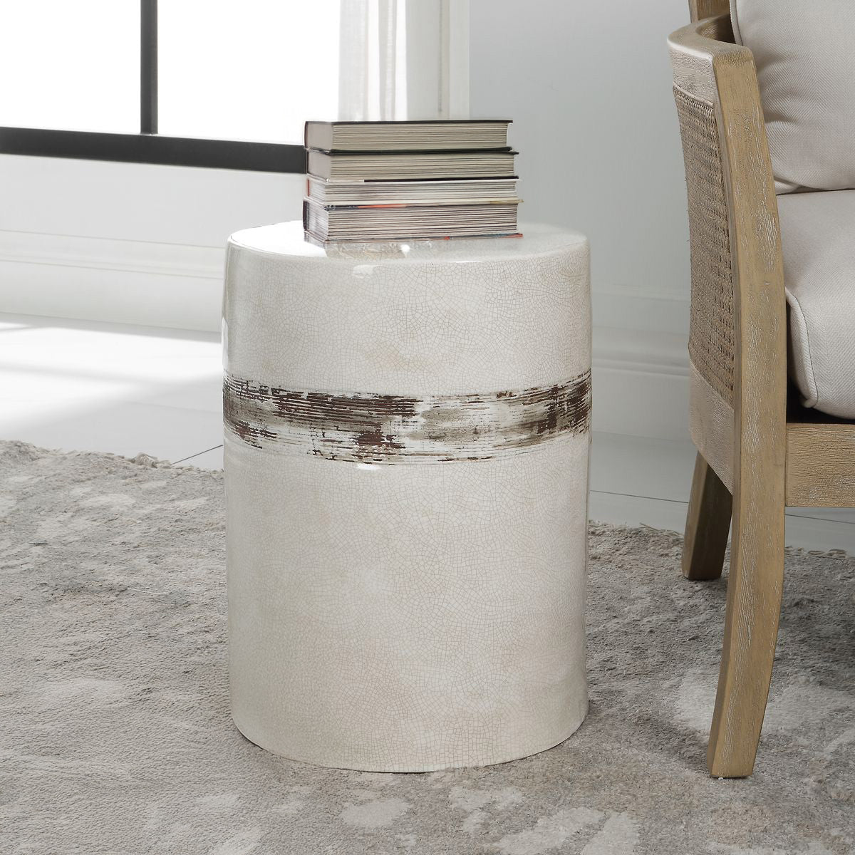White ceramic side table with books on top in living room with carpet and chair.