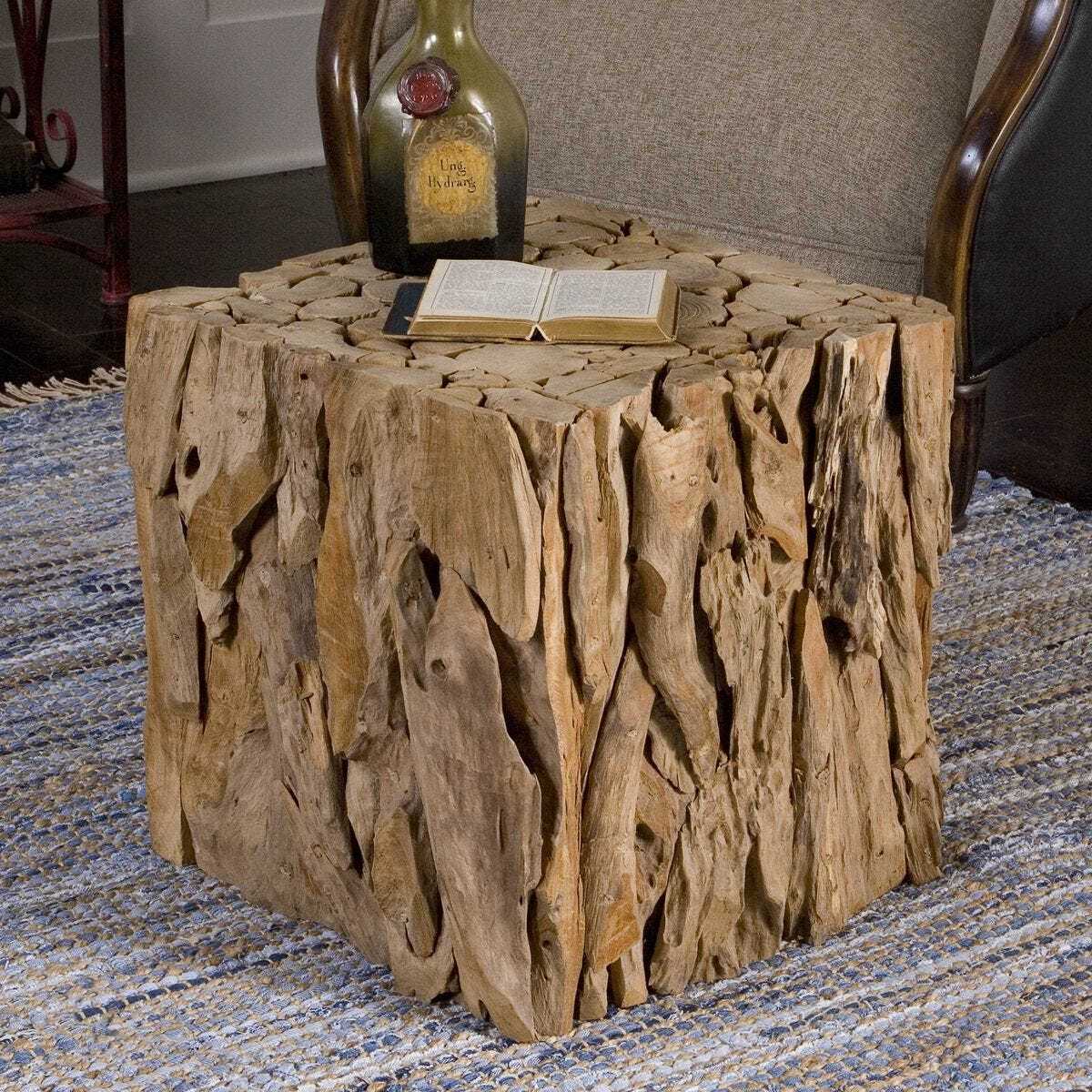 Driftwood side table with a book and bottle on a textured rug