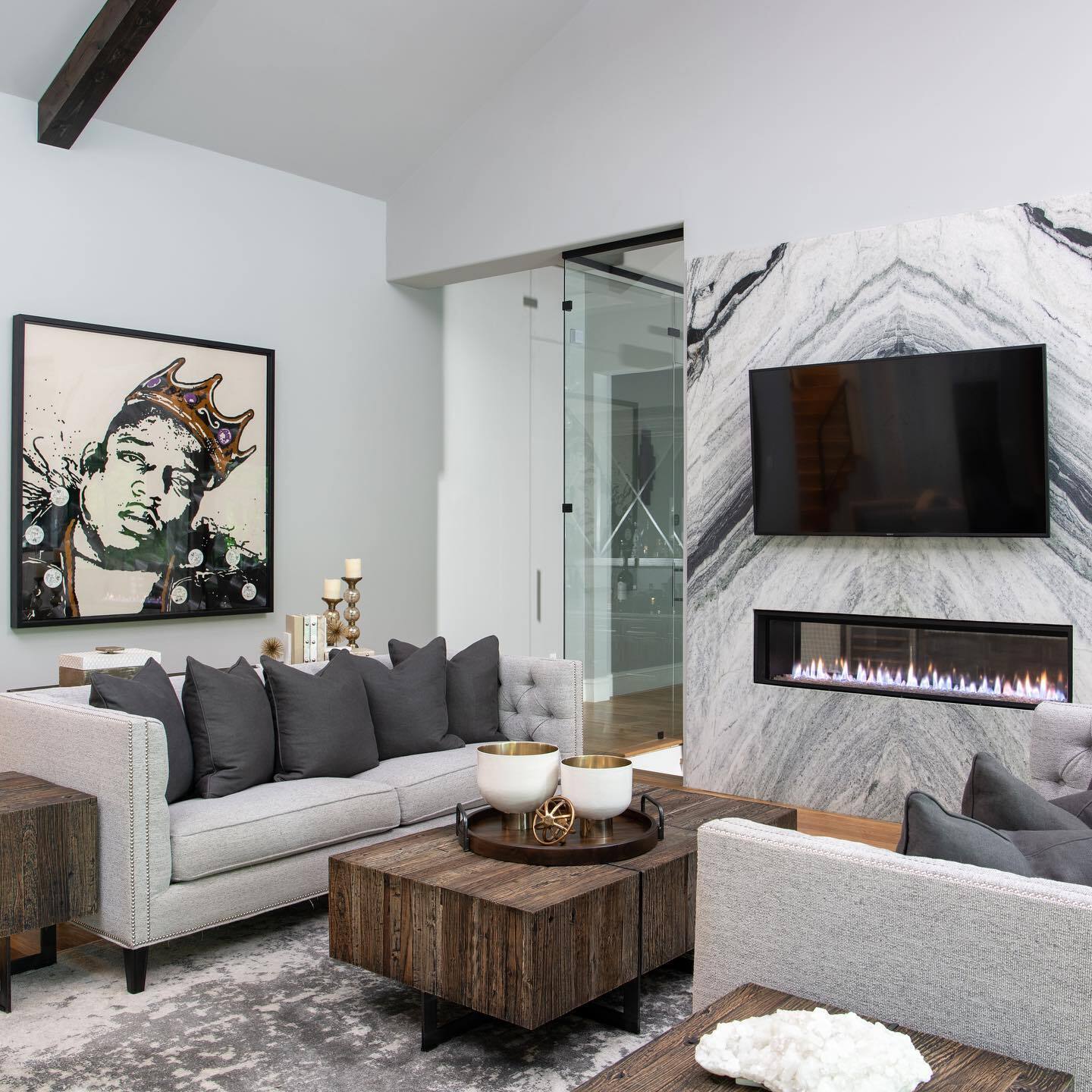 Modern living room with gray sofa, wooden coffee table, and marble fireplace.