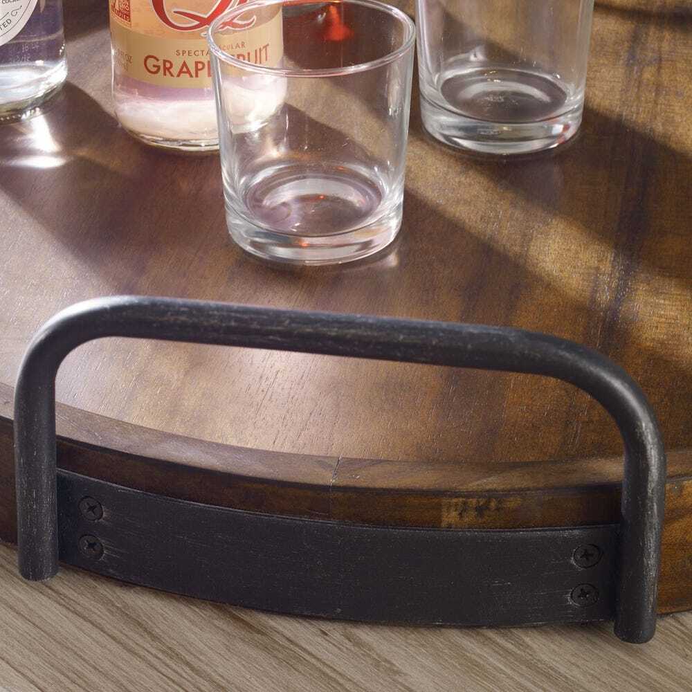 Black metal bottle opener on a wooden surface with glasses and a bottle in the background.