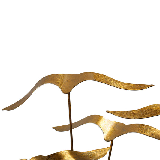 Flock of seagulls, finished in a metallic gold leaf, flying above an aged black distressed wood base.