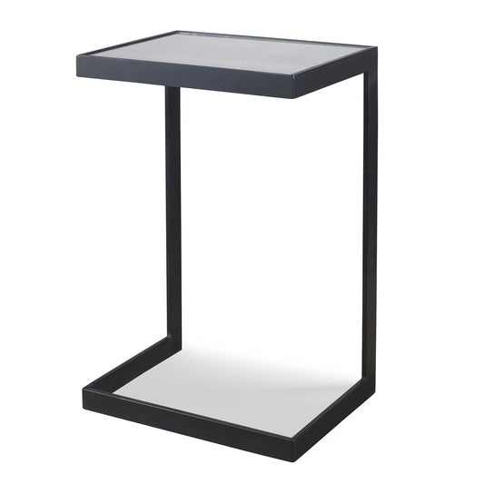 Acantilever designed table with classic style, features thick aged black iron with an open framed base, and a mirrored top with linear antiquing and distressed edges. THis table is nestled up to an occasional chair.