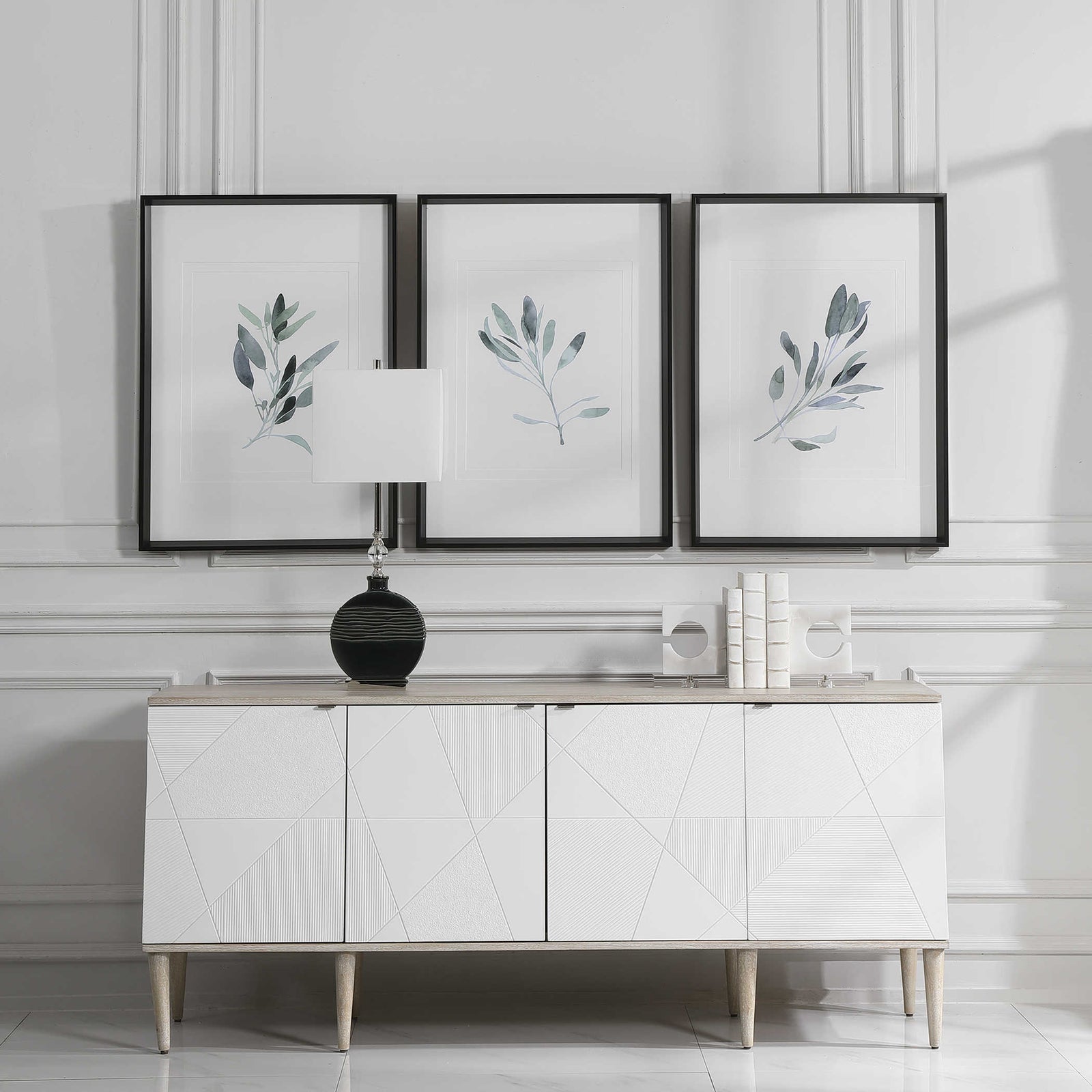 Set of three sage plan prints above a white console in a luxurious living room.