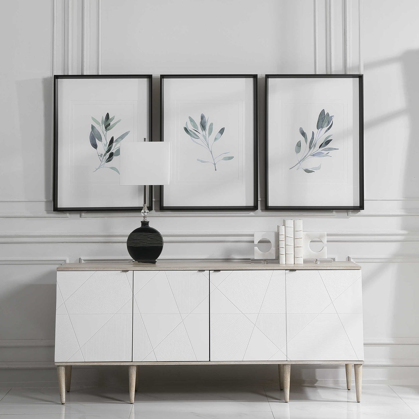 Set of three sage plan prints above a white console in a luxurious living room.