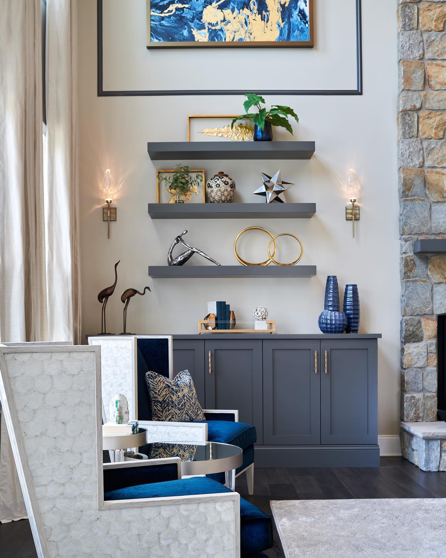 Home decor on floating shelves with decorative chairs.