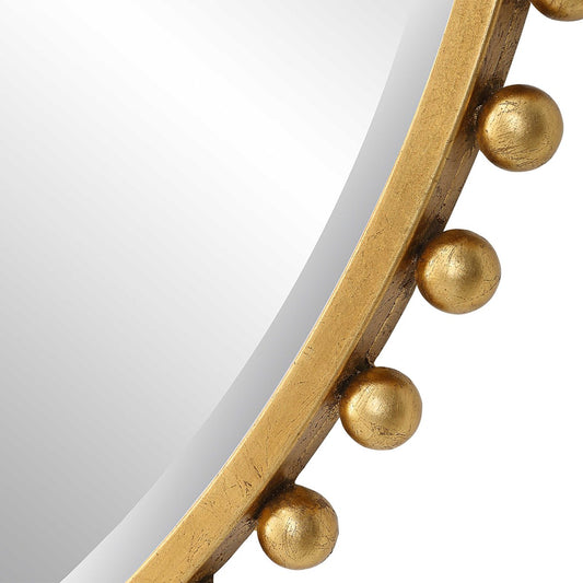 Round mirror with gold embellishments on a white wall above a sink.