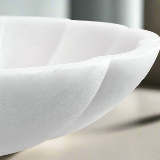 Modern white decorative bowl on white coastal end table with sofa in a coastal living room.