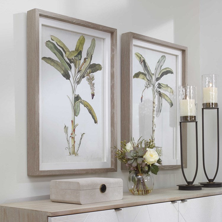 Pair of prints on a wall in front of a console with decorative accents.