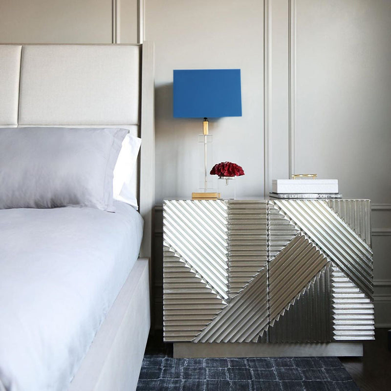 Coral sculptures on top of a side table in a coastal bedroom with blue table lamp.