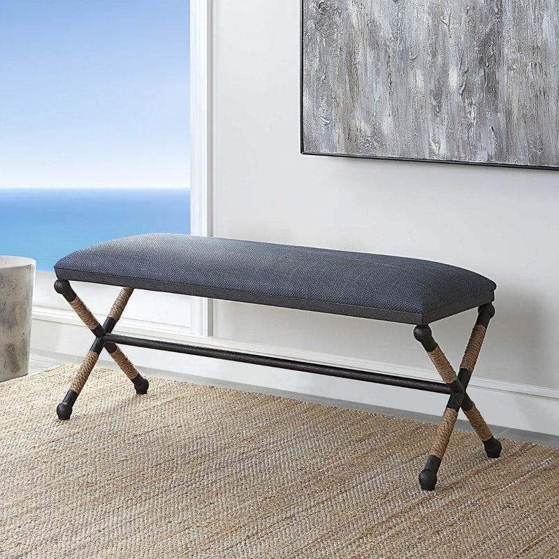 Coastal bedroom with nautical bench and abstract art on a woven beige rug.