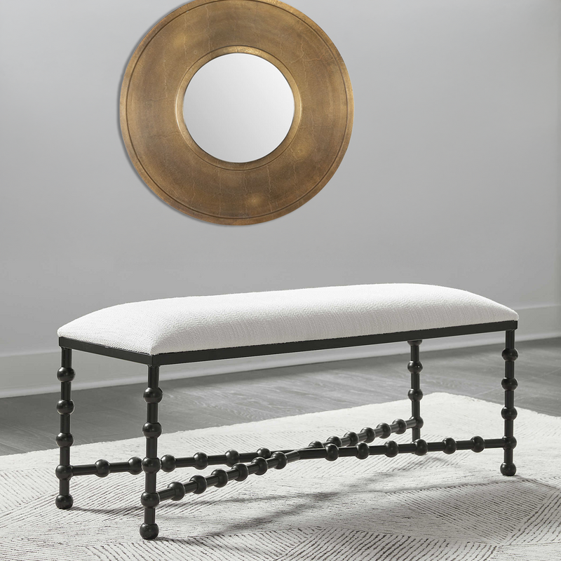 Gold Circle Mirror above white upholstered bench.