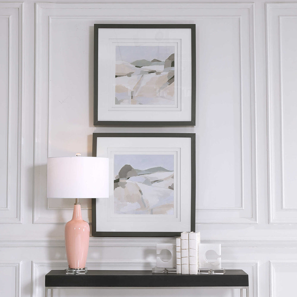 Framed Art in a Coastal Style below a black console and pink lamp.