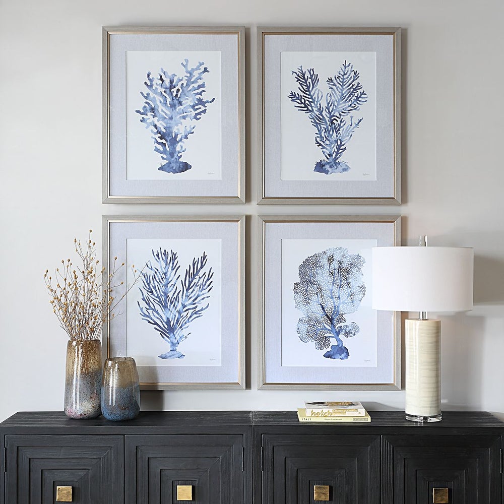 Framed coastal art pieces of coral above black console.