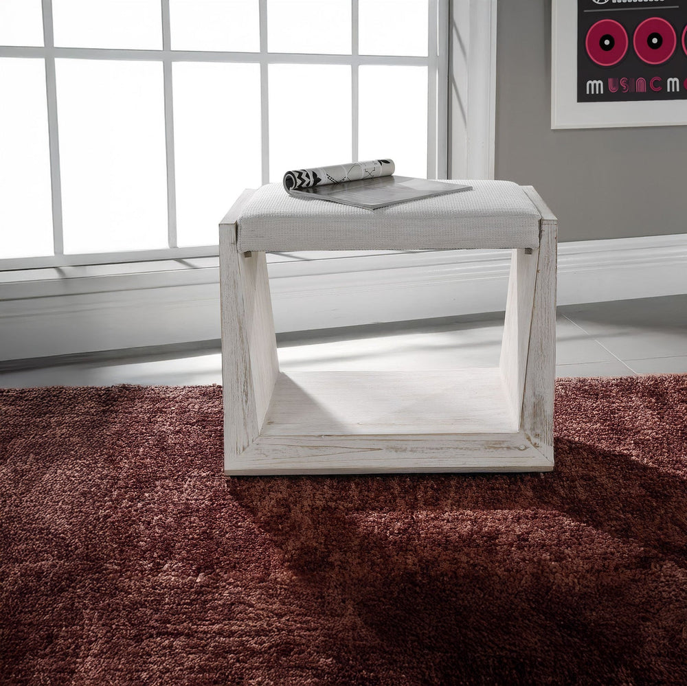 Slim, white entryway bench on maroon carpet. 