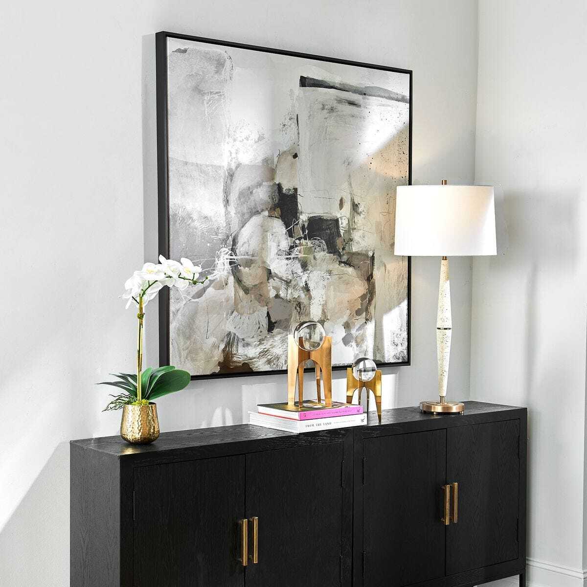 Modern interior with a black console table, abstract art, and decorative items.