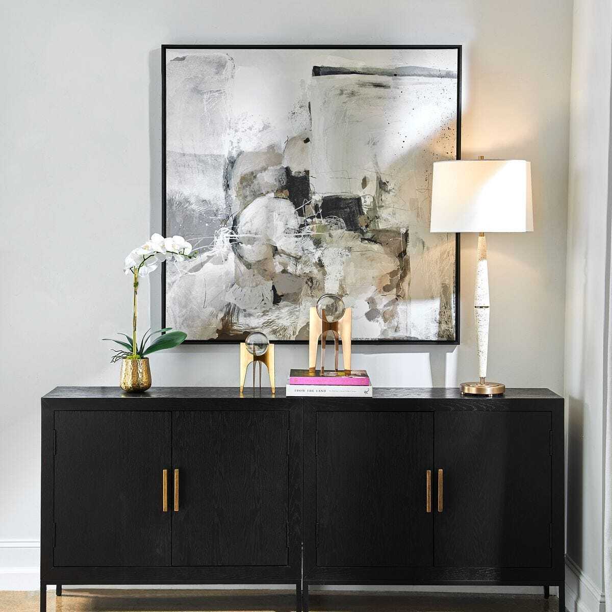 Modern interior with a black sideboard, abstract painting, and decorative items.