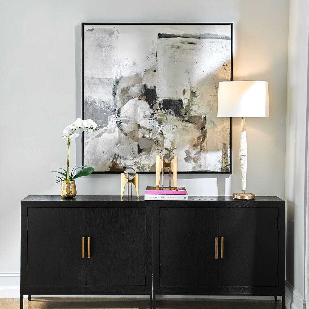 Modern interior with a black sideboard, abstract painting, and decorative items.