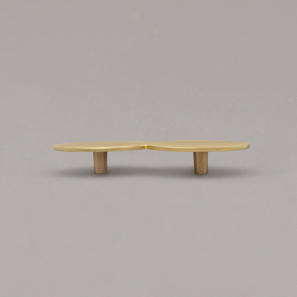 Satin brass cabinet pull with a unique design on a gray background