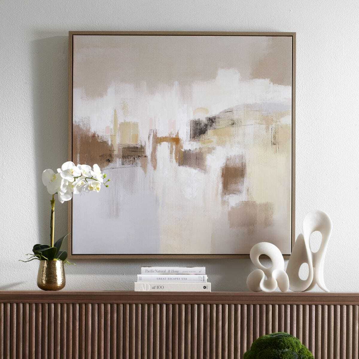 Abstract painting on a wall above a wooden console table with decorative items.