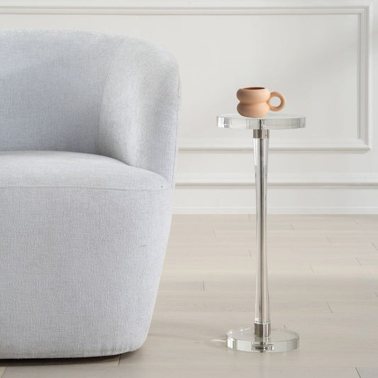 Acrylic drink table next to gray sofa and a ceramic terracotta mug in a white living room.