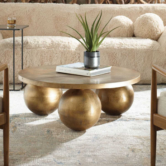 Bronze-colored round table with spherical bases on a white background