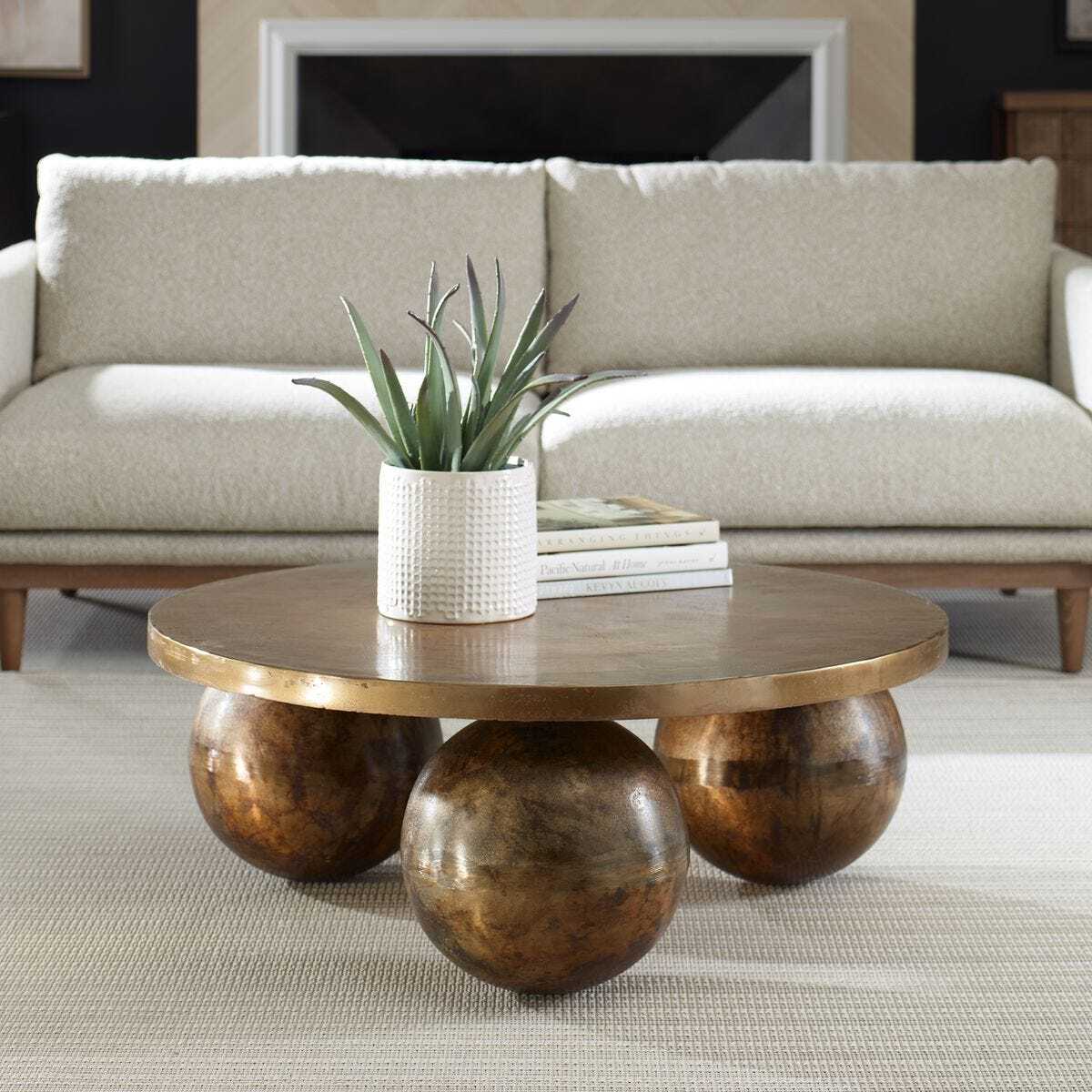 Metal antique brass coffee table with spherical bases in a living room setting