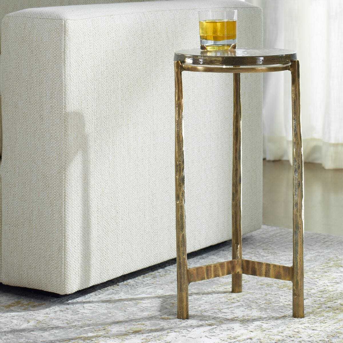 Small metal side table with a glass of orange juice next to a white upholstered chair.