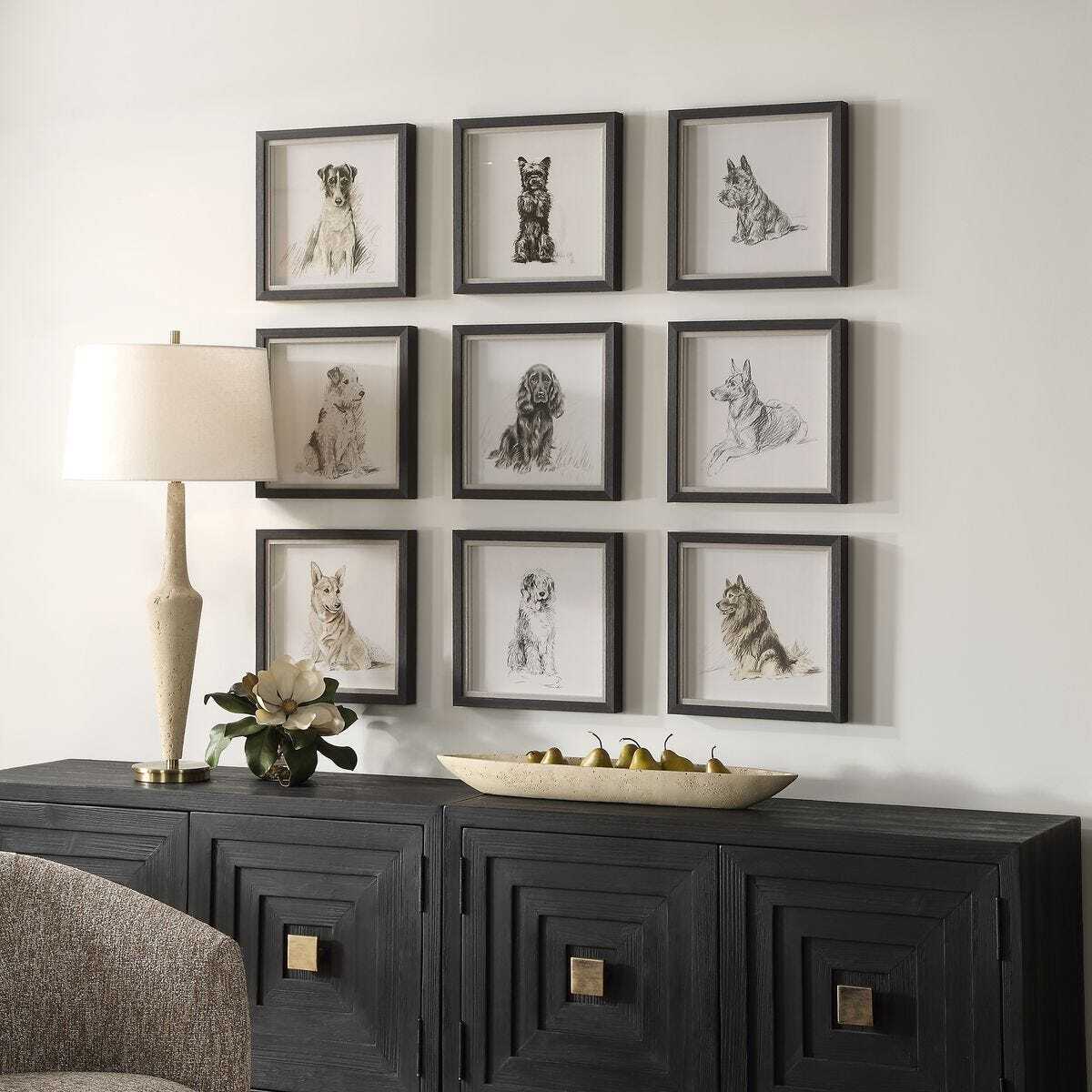 Wall with framed black and white photos of dogs above a dark wooden console table.