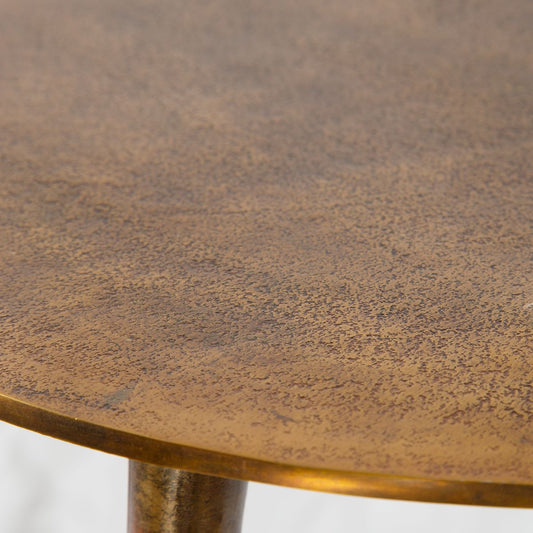Set of three nesting coffee tables are made from cast aluminum with noticeable texture and are finished in oxidized antique gold next to white sofa.