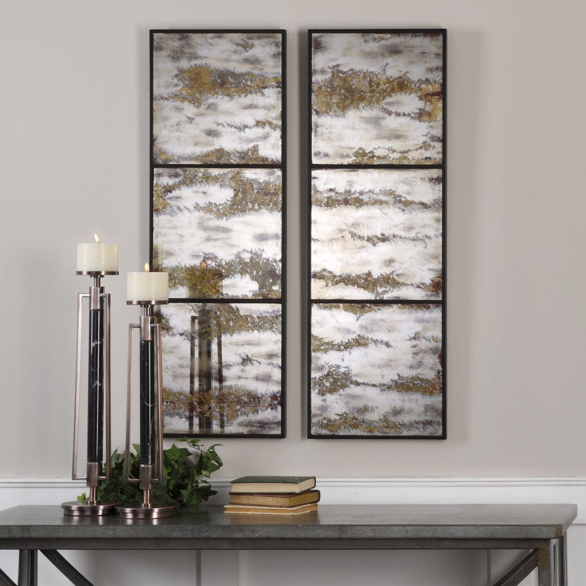 Set of four abstract wall art pieces on a gray wall above a table with decorative items.
