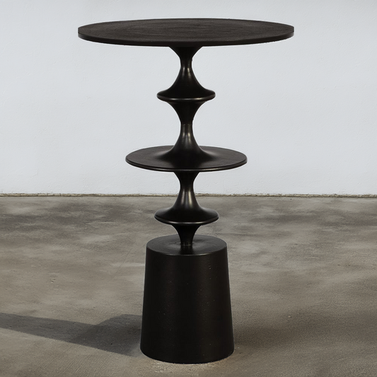 Round black metal accent table on a concrete floor and white background.