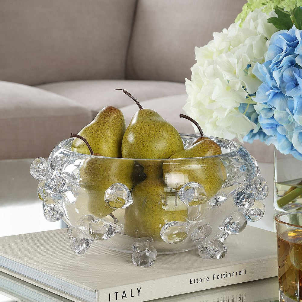 Clear glass bowl with pears on a table with flowers in the background