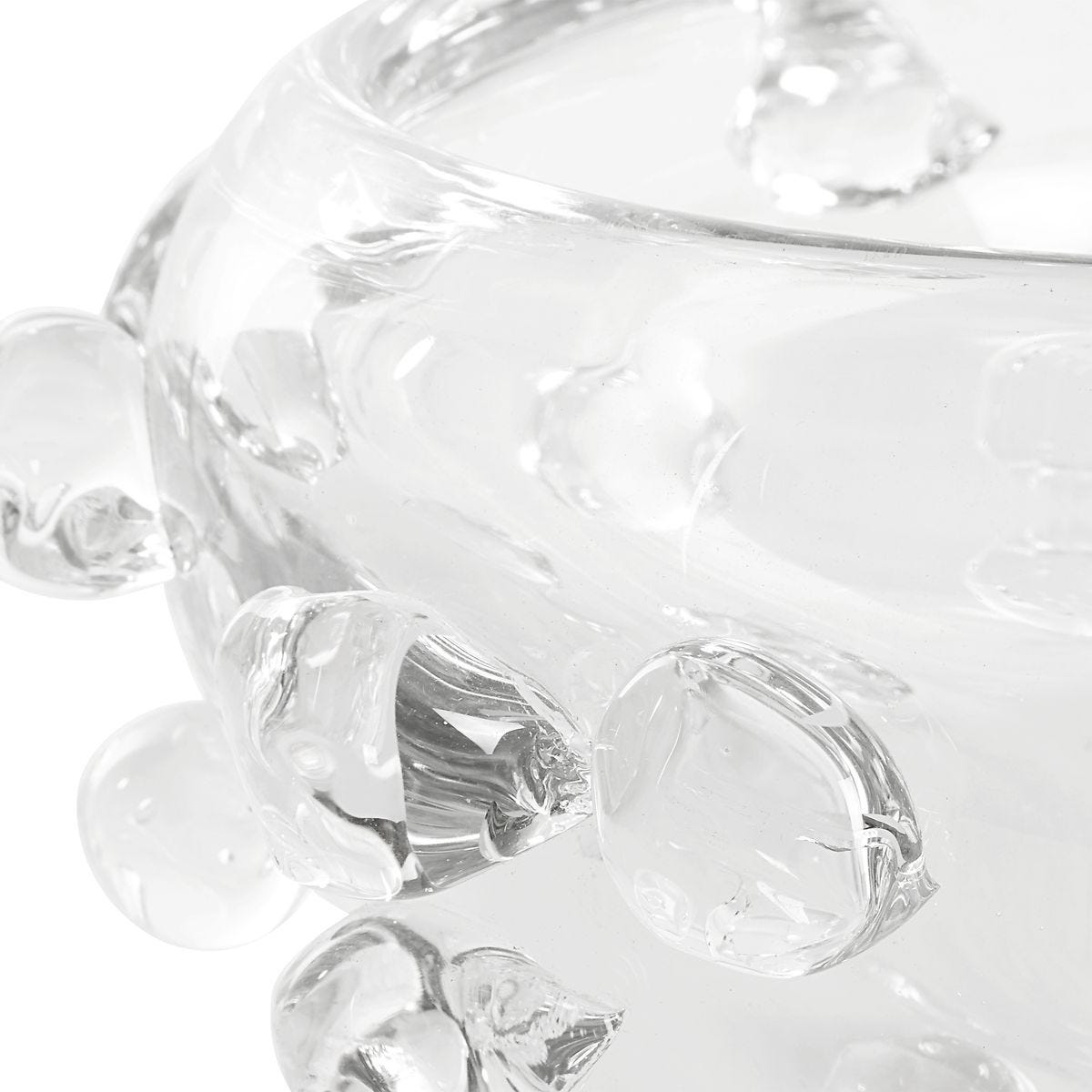 Close-up of a clear glass candy dish with decorative elements on a white background