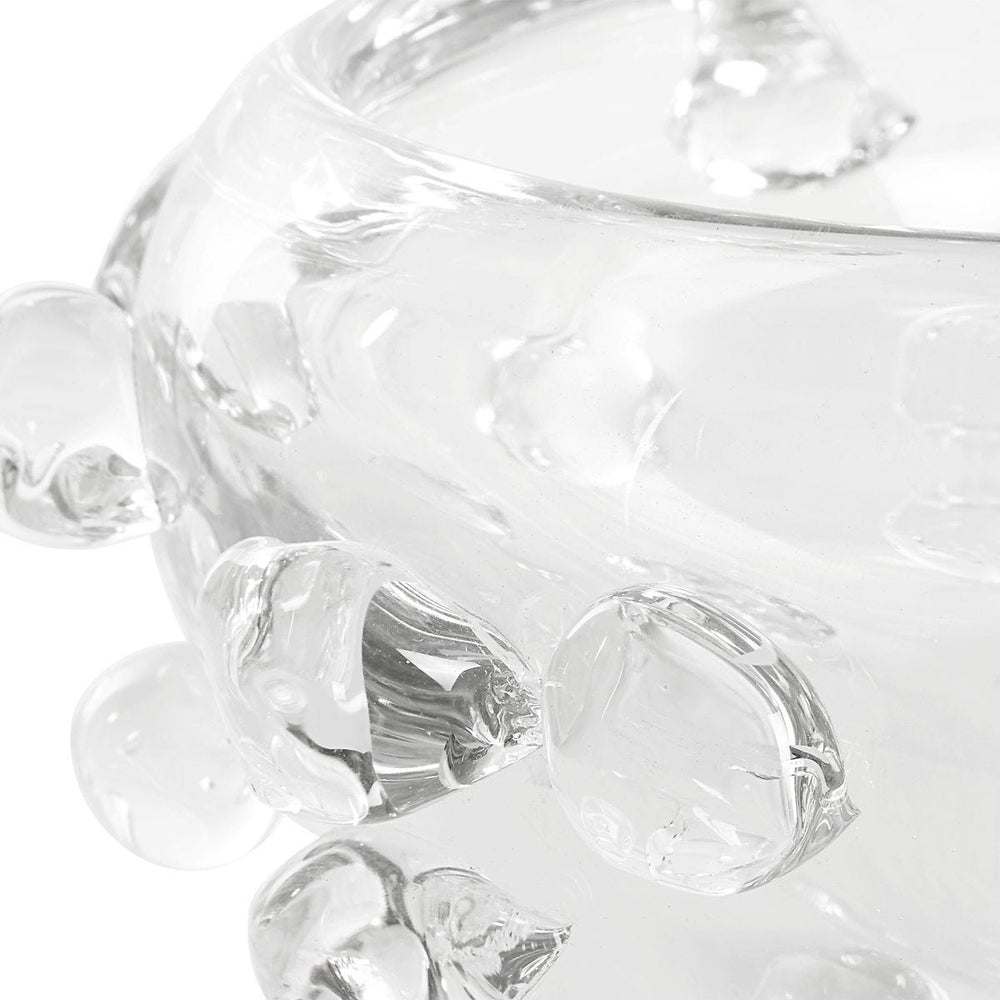 Close-up of a clear glass candy dish with decorative elements on a white background
