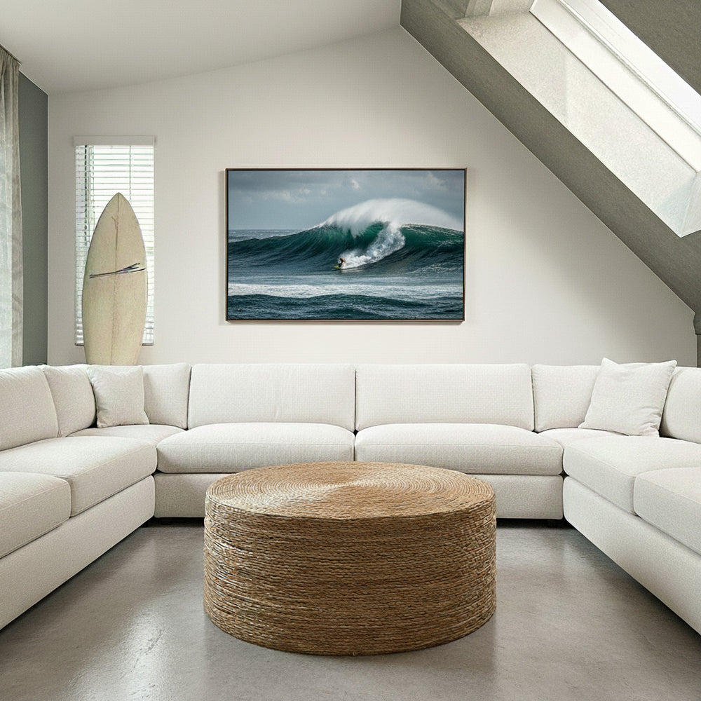 Modern living room with a white sectional sofa, round woven coffee table, and a television displaying a wave.