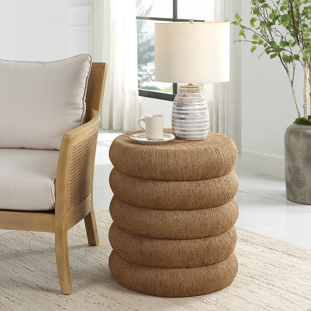 Stacked woven side table in a living room setting with a chair, lamp, and plant.