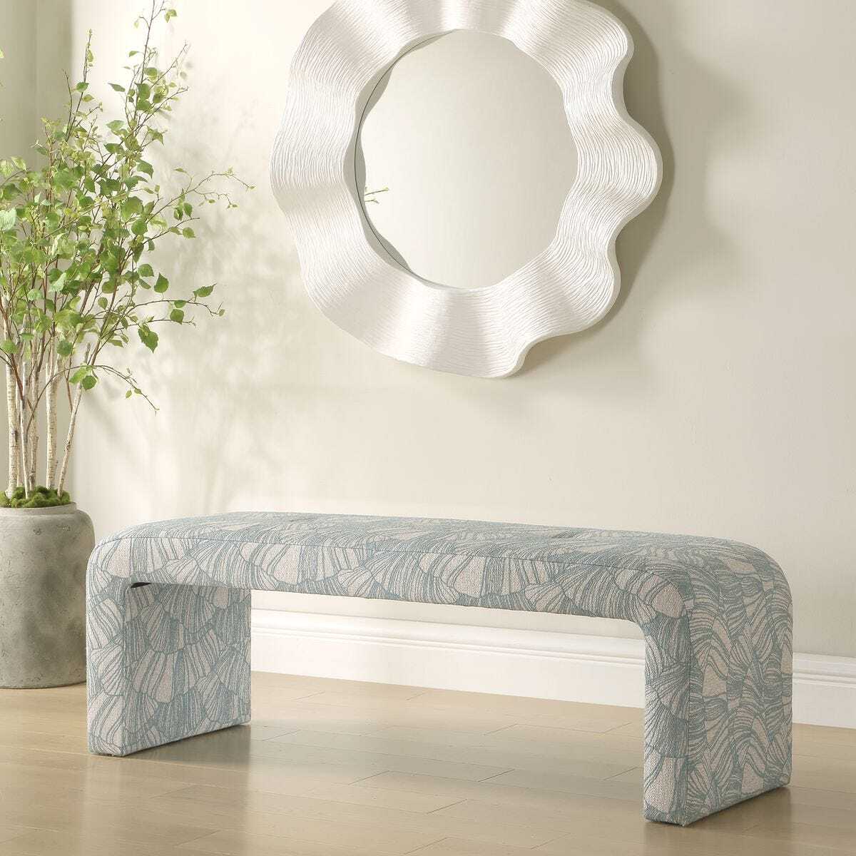 Decorative bench with a patterned design in a room with a mirror and plant.
