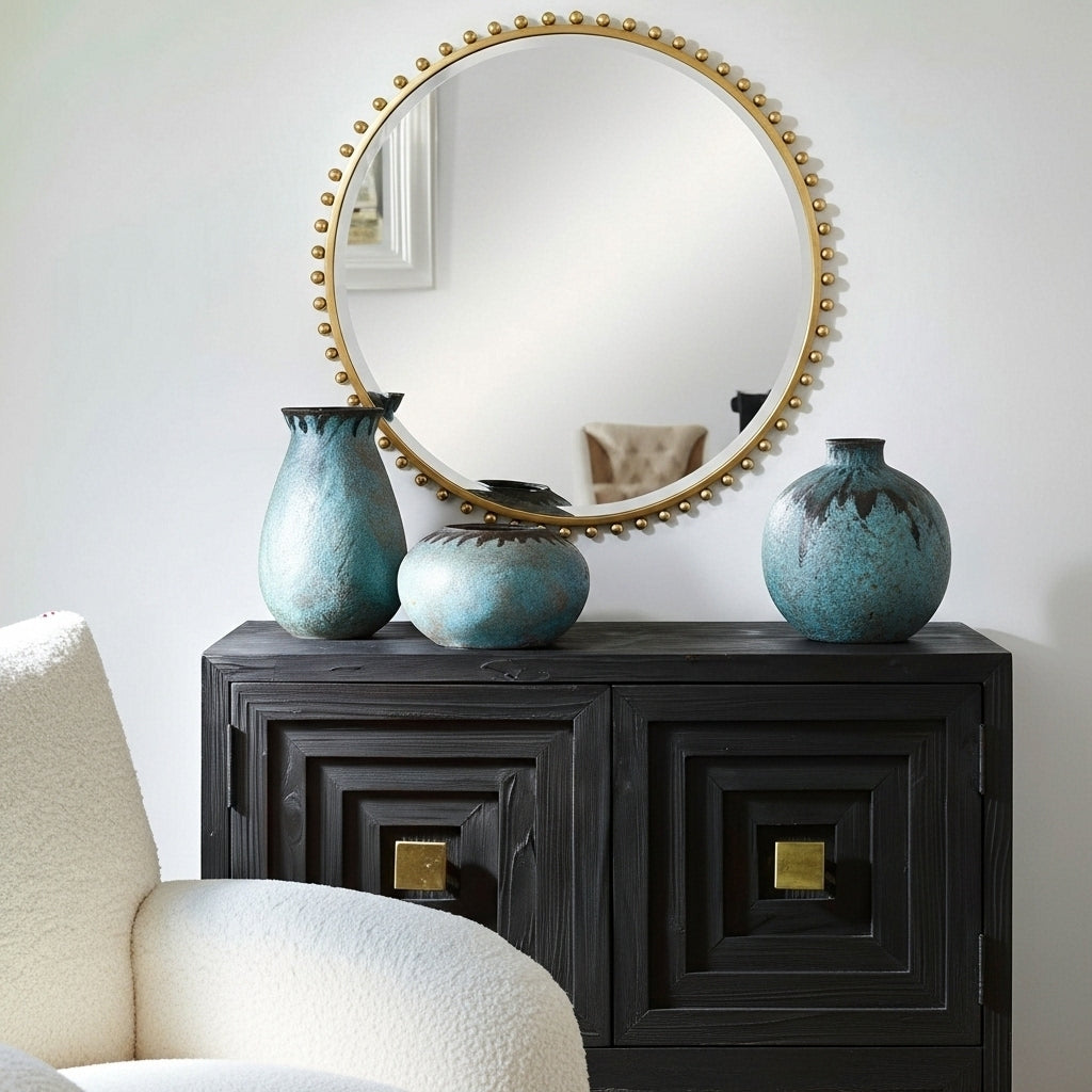 Decorative setup with a round mirror, black console table, and blue vases against a white wall.