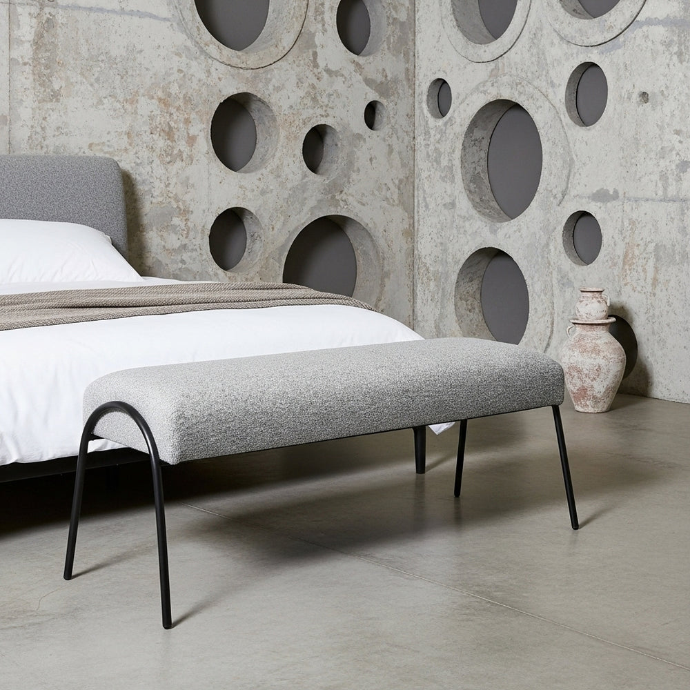 Gray upholstered bench in a modern bedroom with concrete wall design
