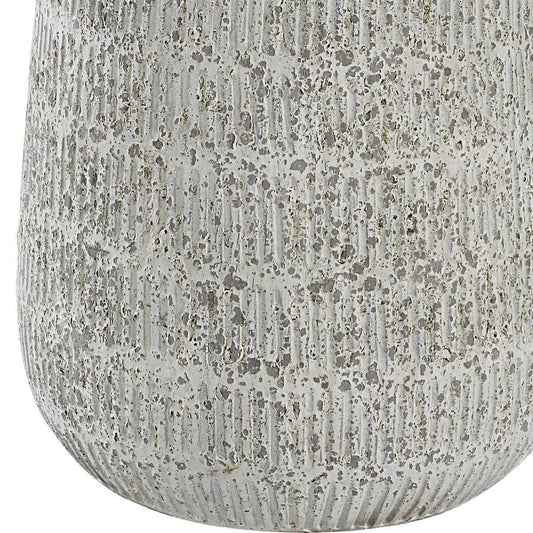 A table lamp with a textured, speckled off-white ceramic base and a large white drum shade, set against a clean white background.