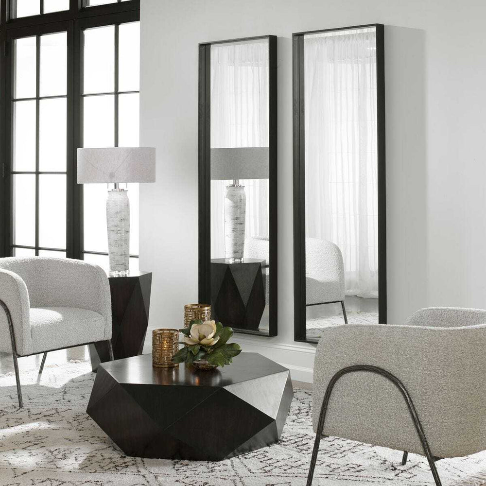 Modern living room with gray chairs, a black coffee table, and large mirrors on the wall.