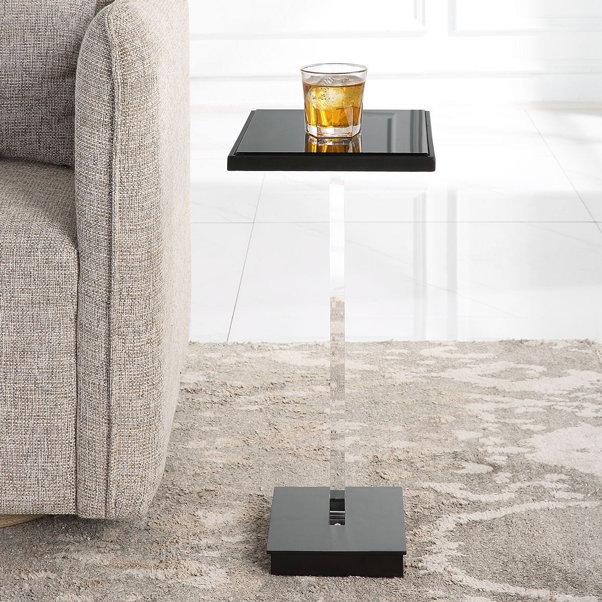 Modern side table with a glass of whiskey next to a sofa in a living room.