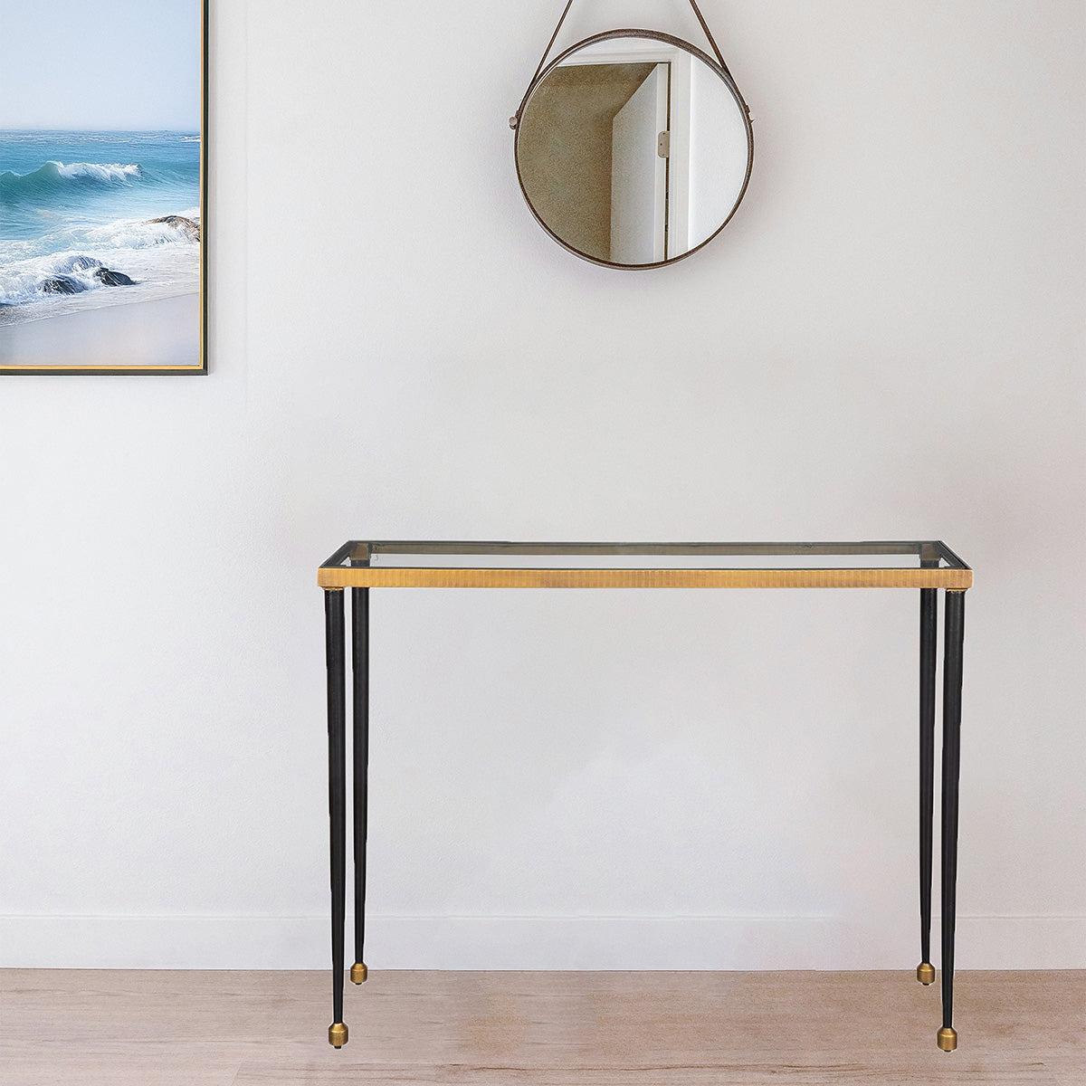 Black and Gold Console with Glass Top in a living room with modern rug and ocean art and mirror.